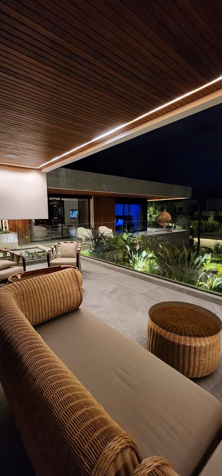 Terrasse couverte, banquette et assises en rotin face au jardin